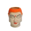 A cream-colored ceramic Buddha head planter with a vibrant orange textured crown holding a green succulent plant