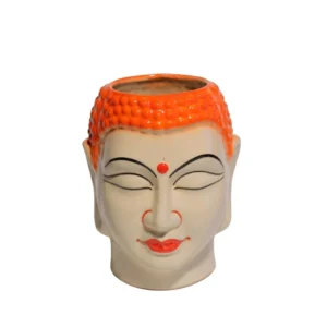 A cream-colored ceramic Buddha head planter with a vibrant orange textured crown holding a green succulent plant