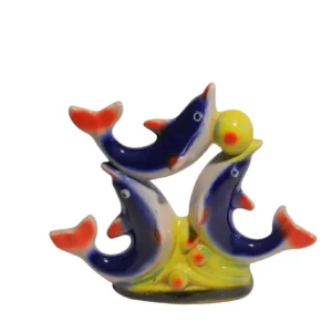 A vibrant ceramic showpiece featuring three blue and orange dolphins leaping around a yellow ball