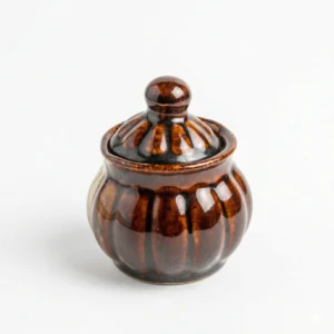 A handcrafted 200ml dual-tone ceramic jar with a glossy brown lid and top and a cream base, isolated on a white background.