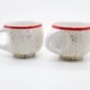 A symmetrical front-facing shot of two rustic ceramic mugs showing the wide ergonomic handles and the unique hand-glazed earthy drip pattern