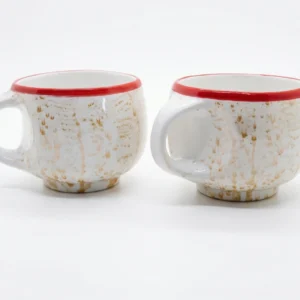 A symmetrical front-facing shot of two rustic ceramic mugs showing the wide ergonomic handles and the unique hand-glazed earthy drip pattern