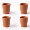A set of four handcrafted red terracotta water cups arranged together on a white background.