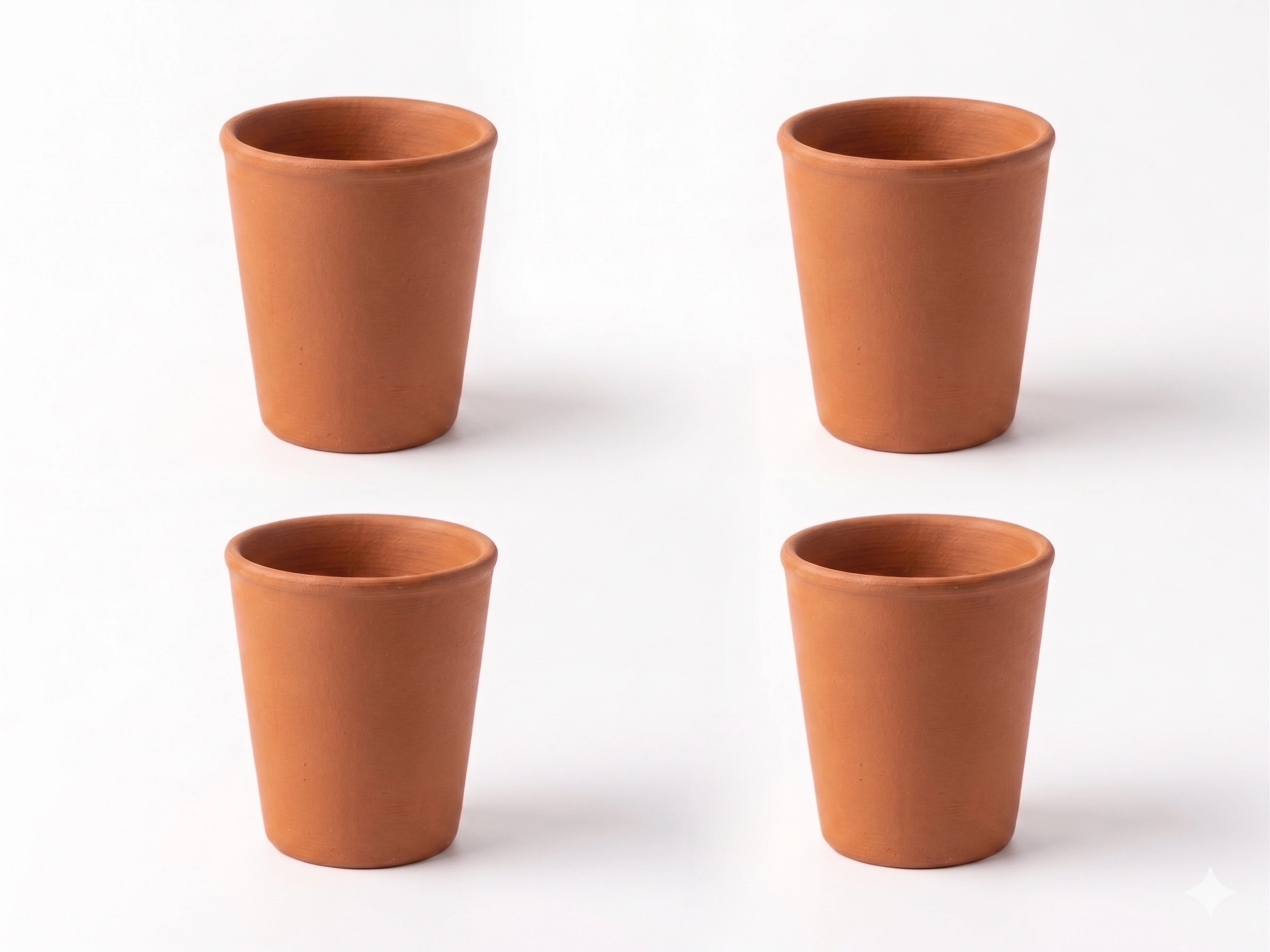 A set of four handcrafted red terracotta water cups arranged together on a white background.