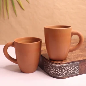 Pair of handcrafted terracotta clay coffee mugs by Vins Art House displayed on a wooden surface.